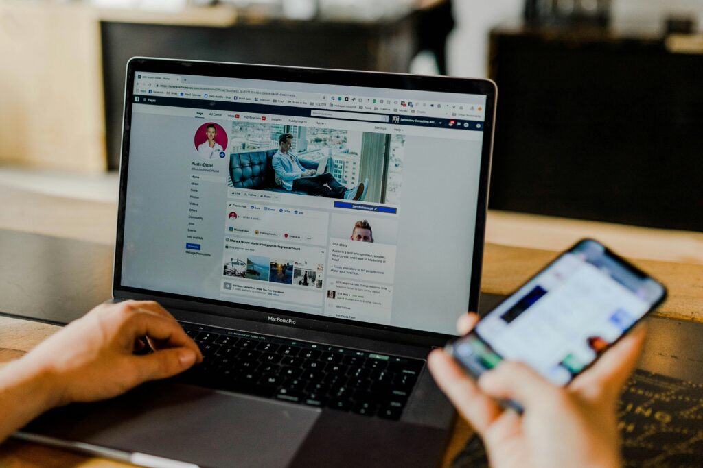 Person using a laptop and phone to manage a social media page.